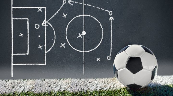 Soccer ball beside a blackboard with a strategy drawn on it with chalk
